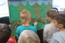 Dzieci przyklejające świstaki na rysunku lasu