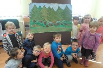 Dzieci siedzące przy rysunku lasu i świstaków