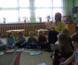 Dzieci oglądające z bibliotekarką książki